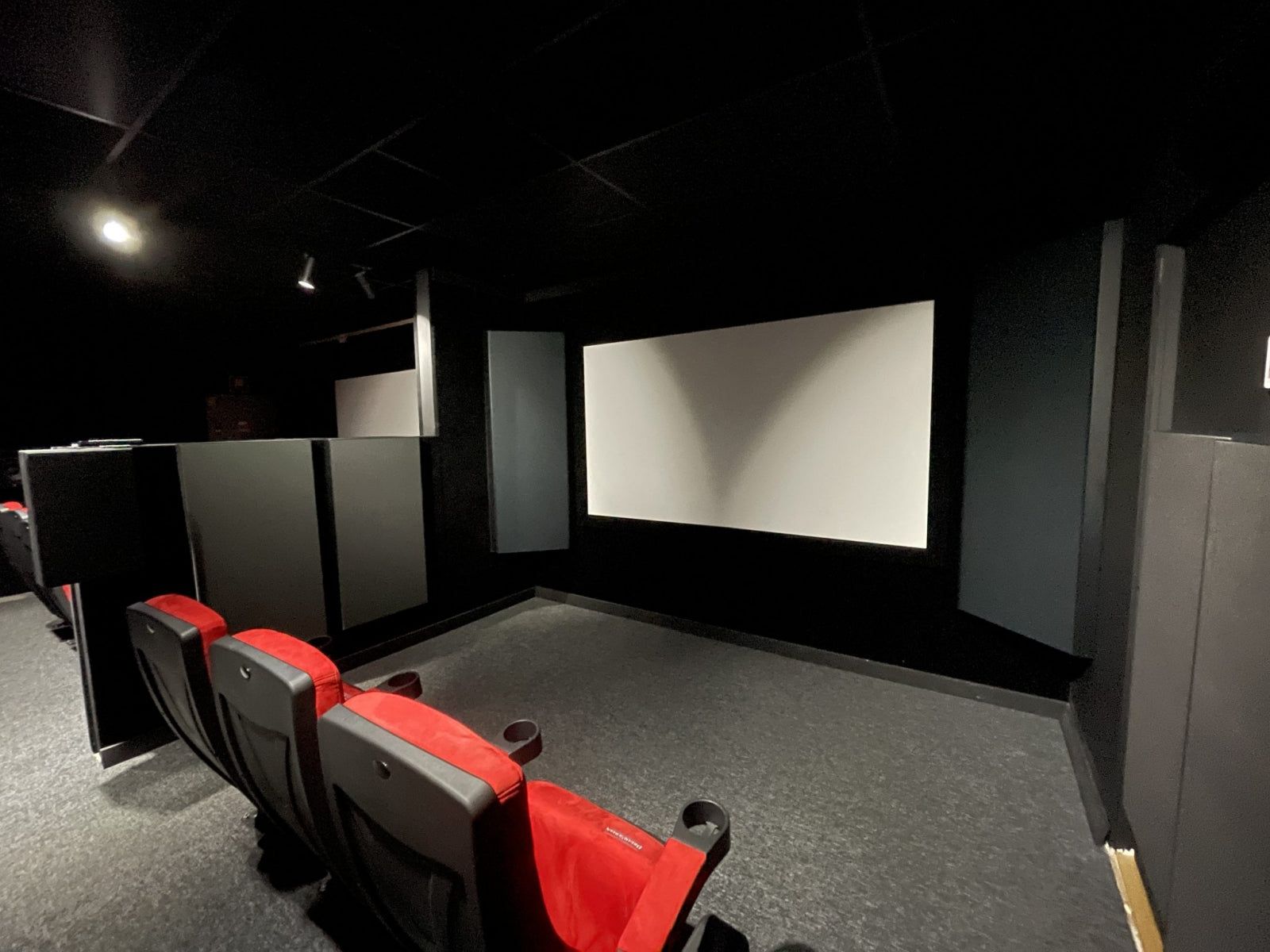 Dedicated cinema room with red seating, projection screen and Vicoustic acoustic panels on the side walls