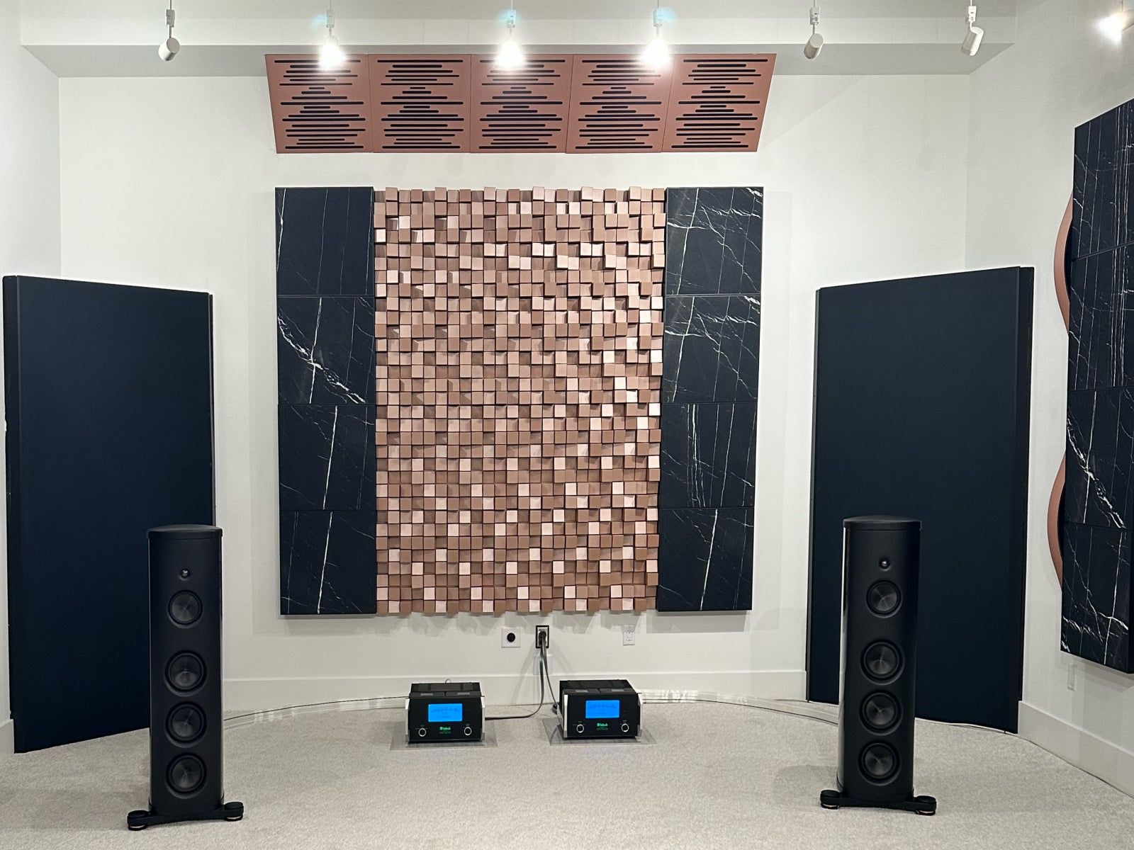 Vicoustic Multifuser diffuser and black acoustic panels behind floor-standing speakers in a listening room