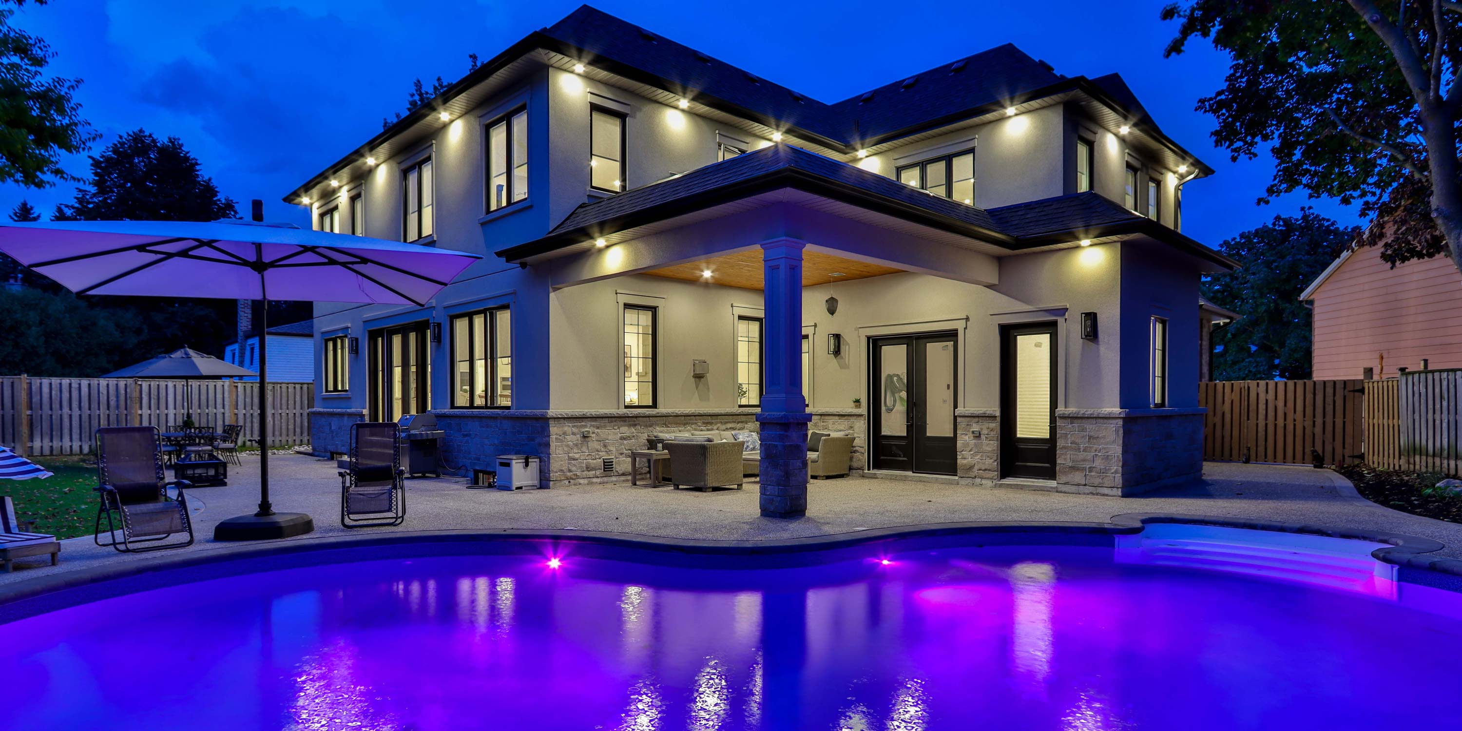 LED lit pool with home at dusk