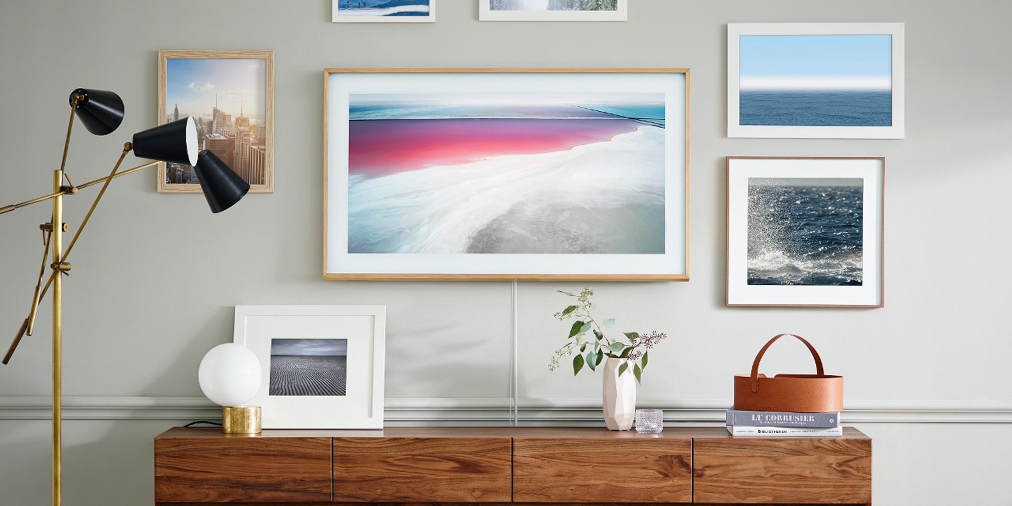 Samsung The Frame TV in Art Mode above a wooden desk with a gallery wall
