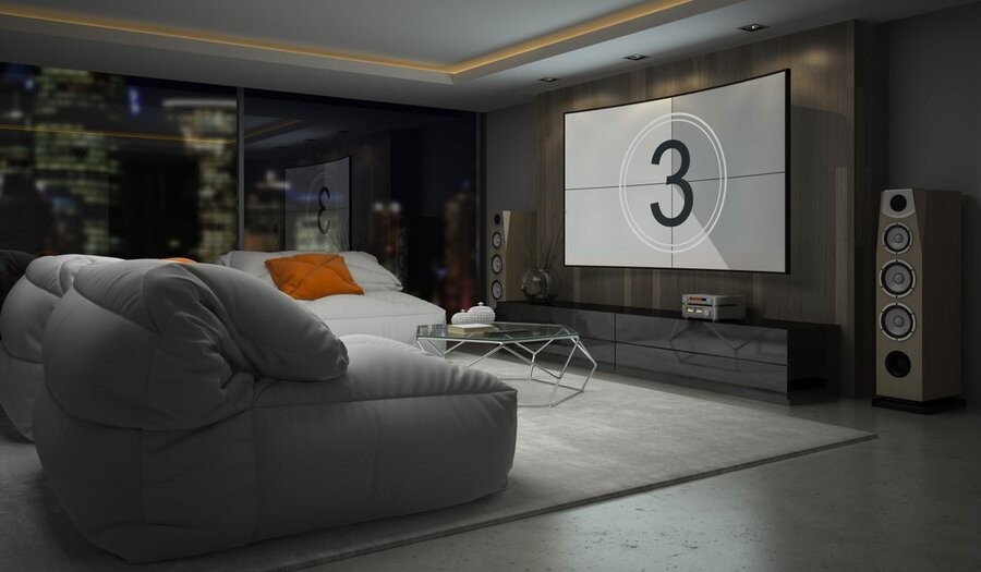 A media room with a large-screen TV, floorstanding speakers, and several plush sofas. 