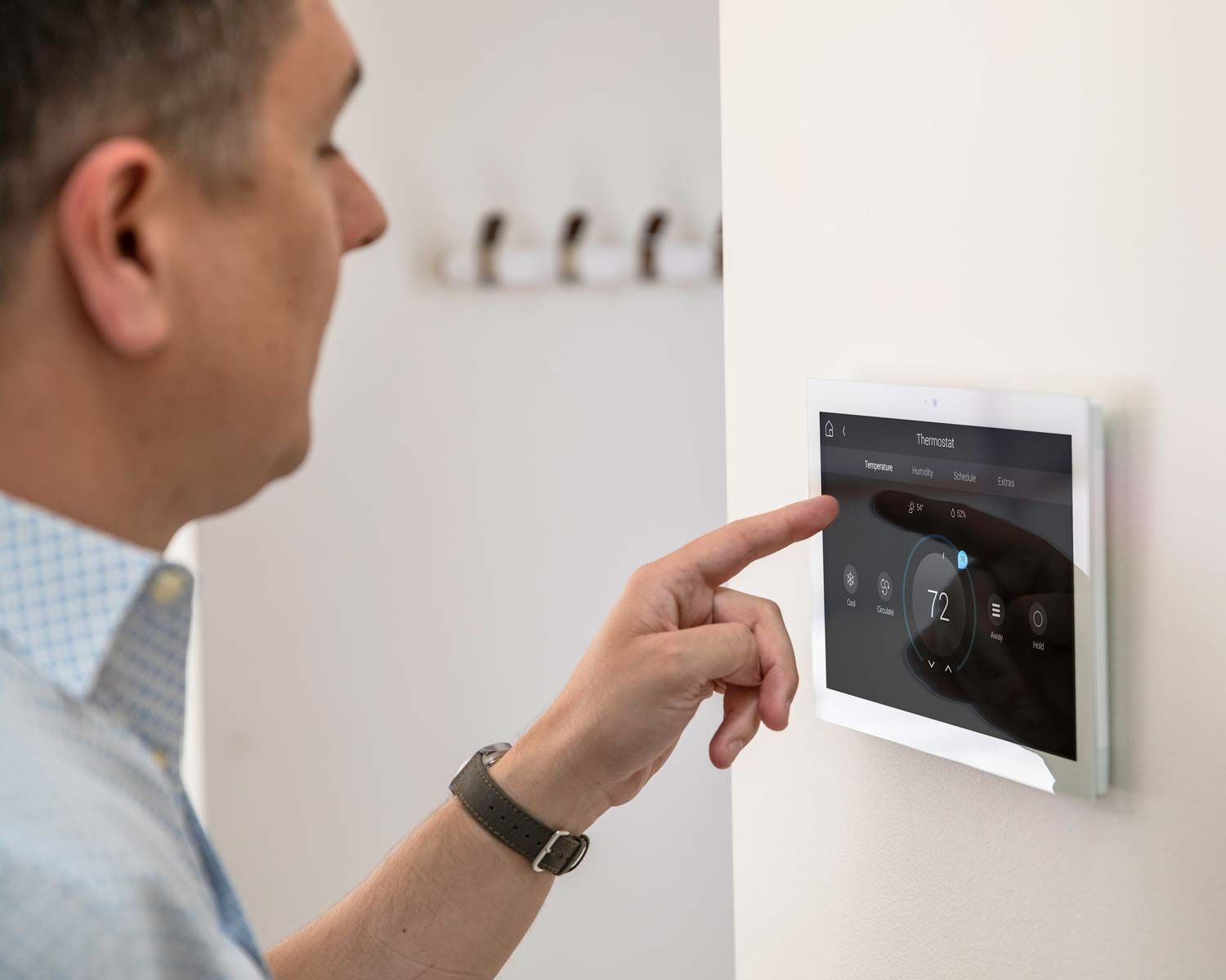 man touching touch panel on wall with control4 thermostat